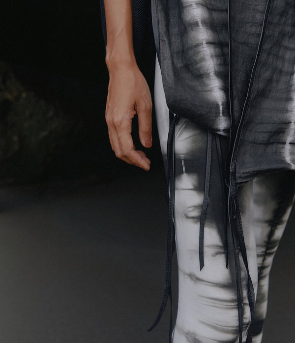 detail of a black and white tie dye linen scarf with leather tassles