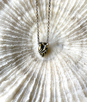 Necklace with a heart shaped pendant on a textured white background.