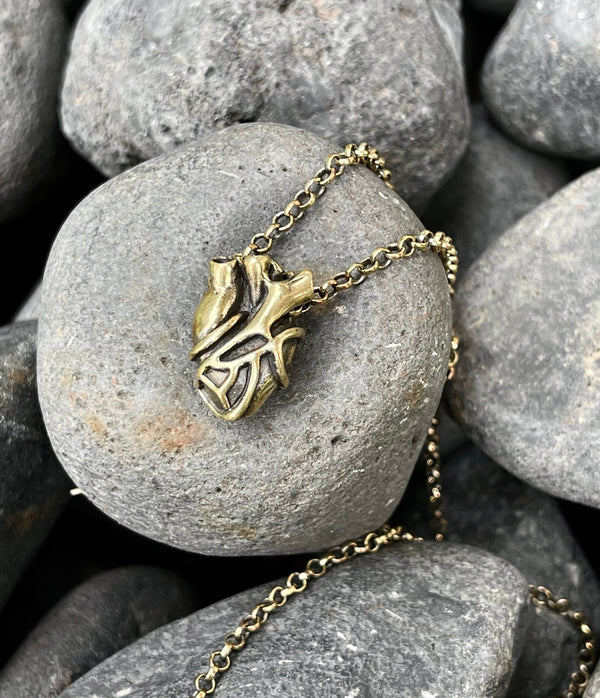 Bronze necklace with a heart pendant on a stone surface